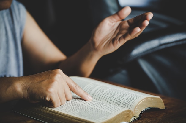 Spirituality and religion, Hands folded in prayer on a Holy Bible in church concept for faith.