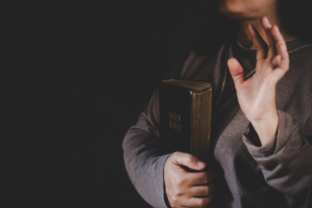 Spirituality and religion, Hands folded in prayer on a Holy Bible in church concept for faith.