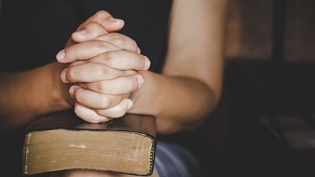 Spirituality and religion, Hands folded in prayer on a Holy Bible in church