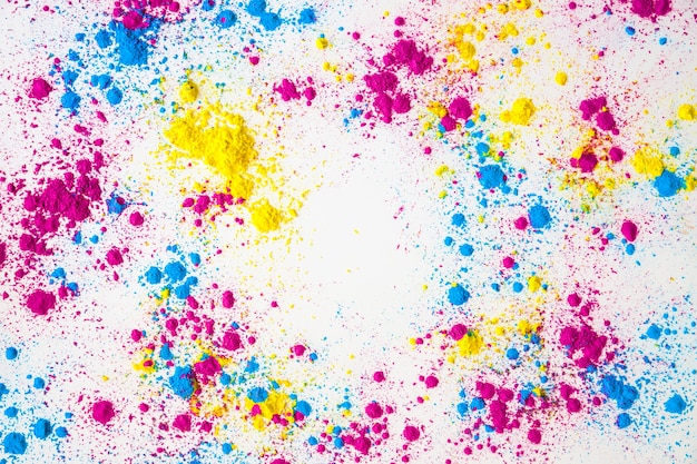 Splatter of yellow; pink and blue holi color powder on white background