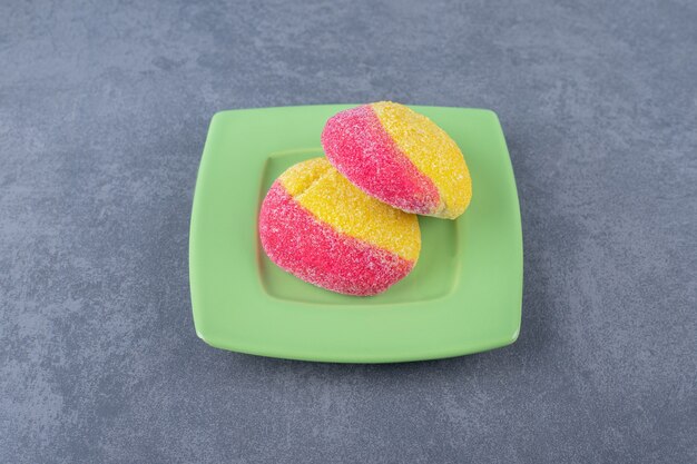 Split peach shaped cookie in half on a plate on marble table.