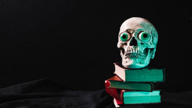 Free photo spooky skull with fancy eyes on pile of books