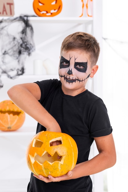 Free photo spooky young boy with evil halloween pumpkin