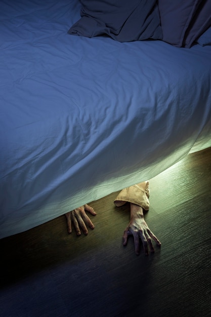 Spooky zombie hands under the bed