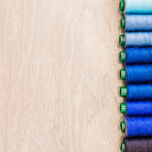 Free Photo spool of threads in row on wooden background