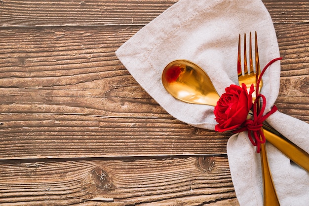 Free photo spoon and fork with red flower on napkin