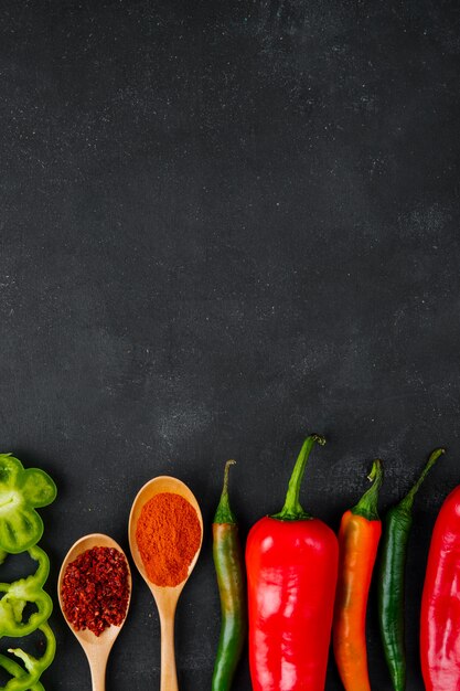 spoons of spices and peppers on black table