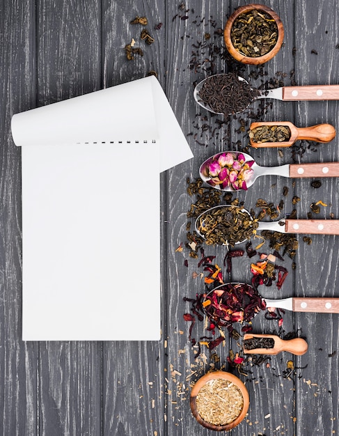 Spoons with herbal tea beside notebook