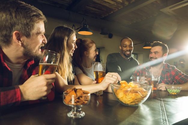 Sport fans cheering at bar, pub and drinking beer while championship, competition is going