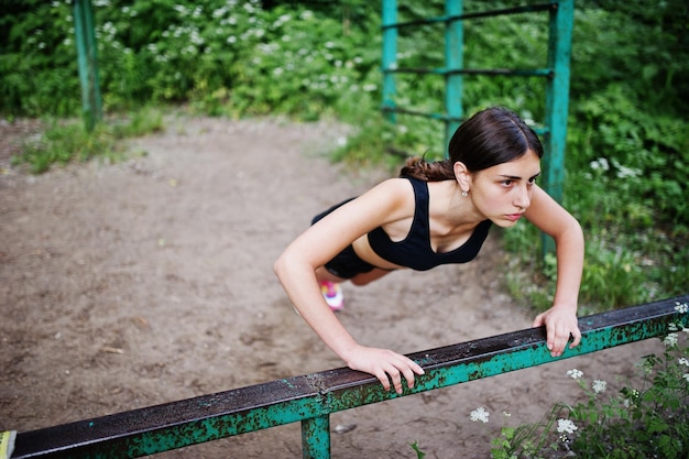 Free Photo sport girl at sportswear exercising at horizontal bar exercises in a green park and training at nature a healthy lifestyle