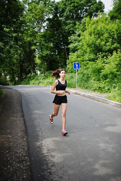 Sport girl at sportswear running in a green park and training at nature A healthy lifestyle