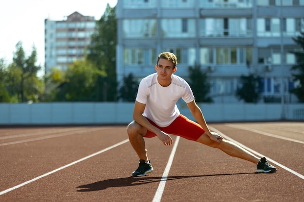 Sport training. Young Caucasian sportive man, male athlete, runner practicing alone at public stadium