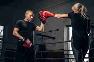 Free photo sportive blond woman has boxing training with her experienced trainer.