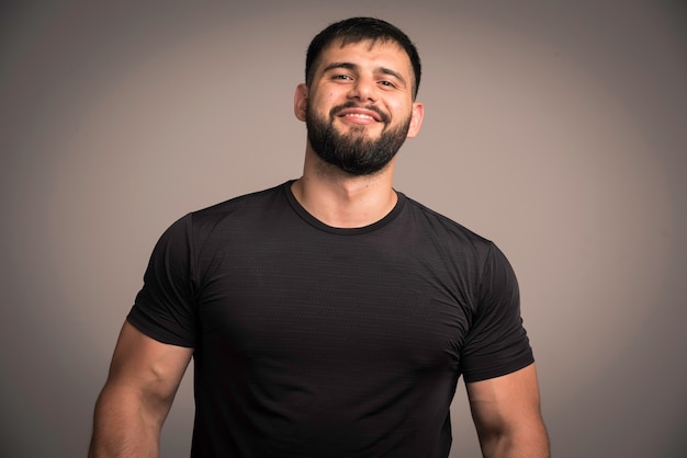 Sportive man in black shirt looks confident and smiling. 