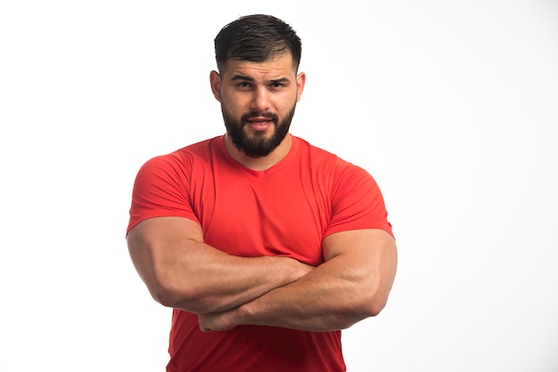 Sportive man in red shirt demonstrating his upper muscles. 