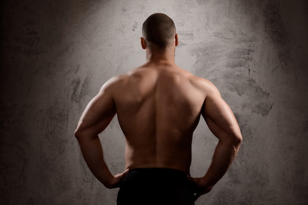 Free photo sportive man's body over dark wall.