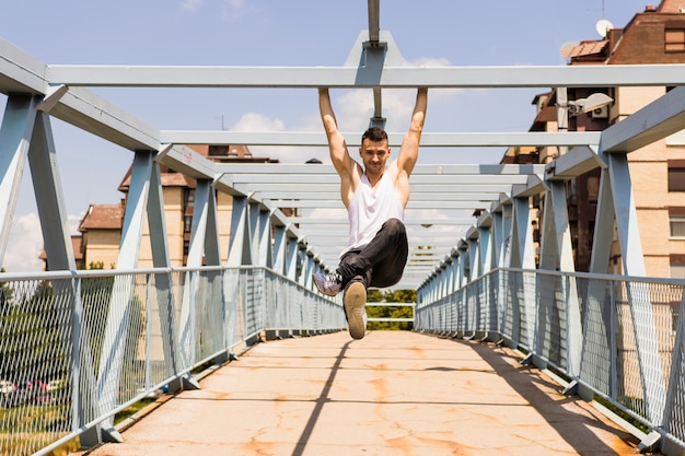 Free photo sportive young man exercising on the bridge