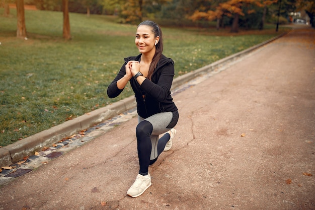 Sports girl in a black top training in a autumn park