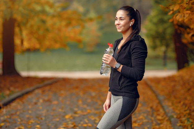 Sports girl in a black top training in a autumn park