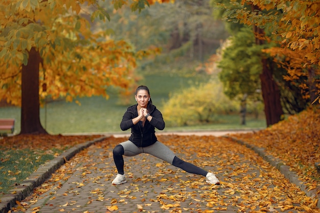 Sports girl in a black top training in a autumn park