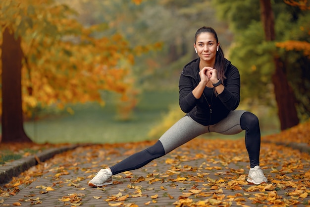 Sports girl in a black top training in a autumn park