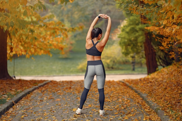 Sports girl in a black top training in a autumn park