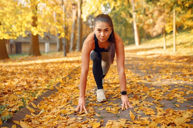 Sports girl in a black top training in a autumn park