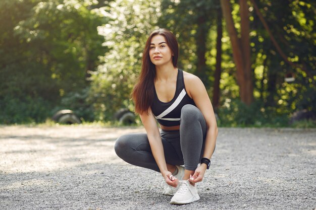 Sports girl in a black top training in a summer park