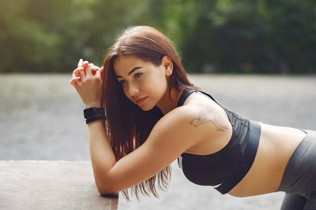 Sports girl in a black top training in a summer park