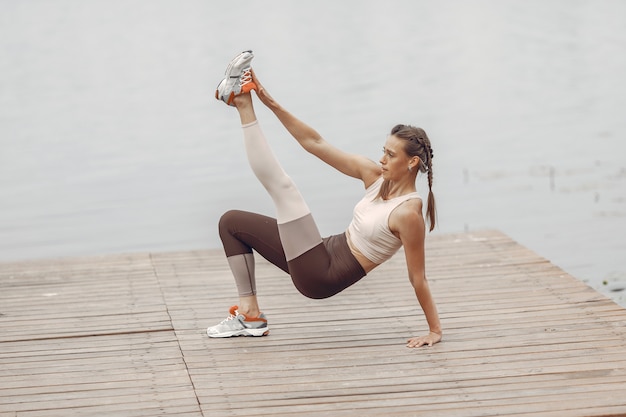 Sports girl by the water. Woman in a summer park. Lady in a sportswear.