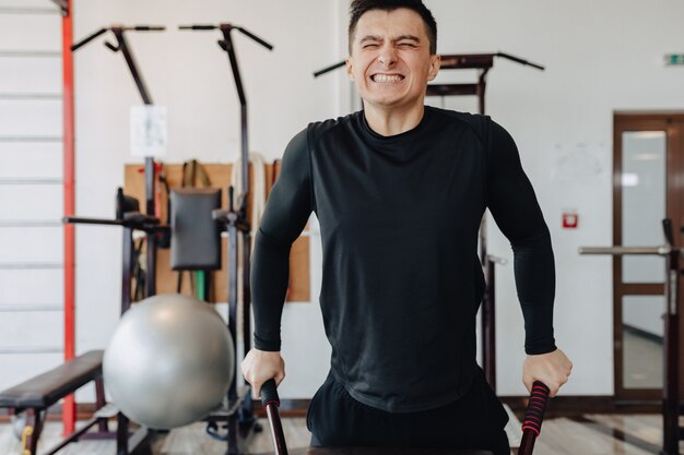 Sports guy squeezes on bars, exercises on pectoral muscles. healthy lifestyle.