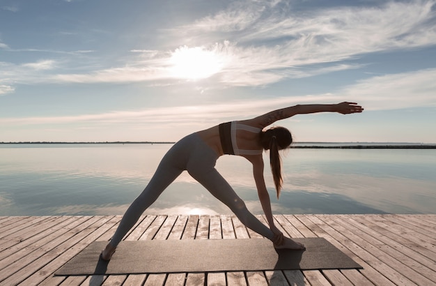 Free photo sports lady standing at the beach make yoga exercises.