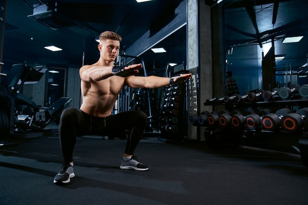 Sportsman doing squats in gym.