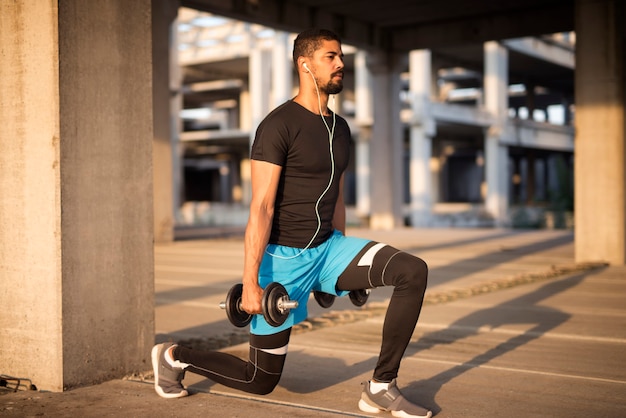 Sportsman listening to music and training with weights