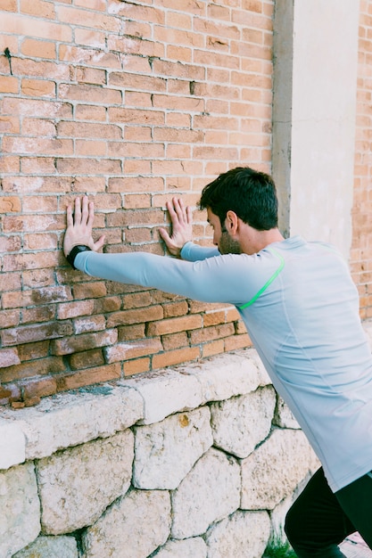 Sportsman performing exercises near wall