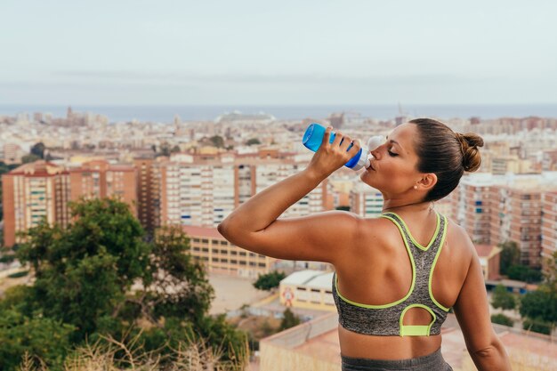 Sportswoman drinking water after training