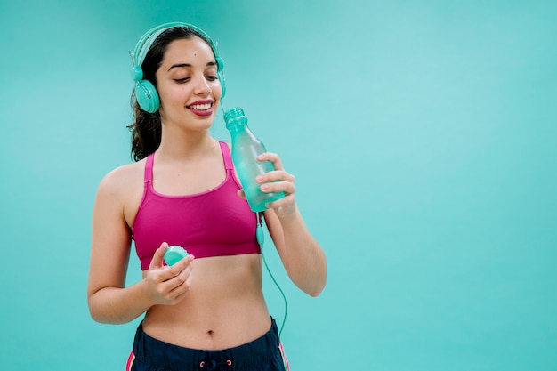 Sportswoman with earphones drinking water