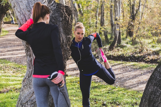 Sportswomen stretching legs outdoors