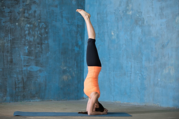 Free photo sporty beautiful young woman doing headstand