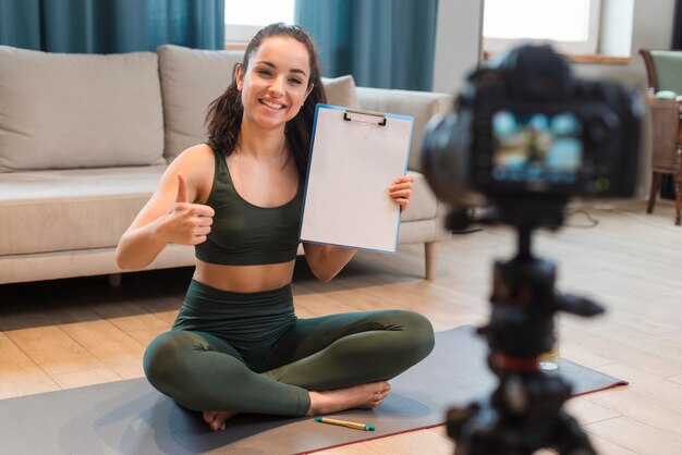 Sporty blogger sitting in front of camera and showing clipboard