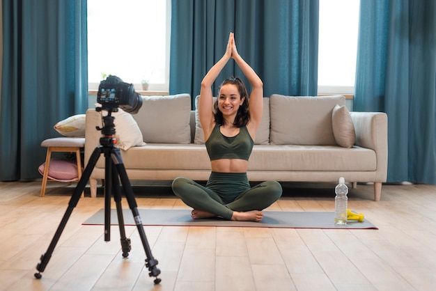 Sporty blogger sitting in lotus position with arms up