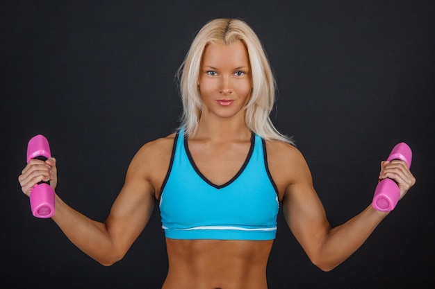 Free photo sporty blond woman with dumbbell isolated on a black background.