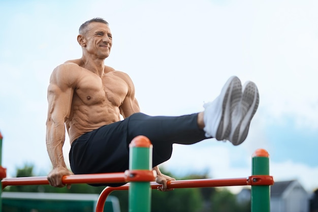 Sporty caucasian man training on parallel bars outdoors