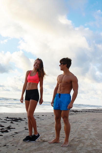 Sporty couple of shirtless man and woman posing on a beach.