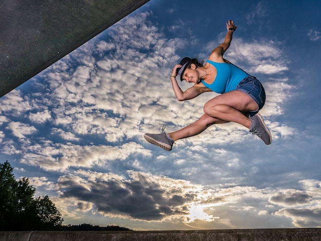 Free Photo sporty european female jumping up in the air on cloudy sky background