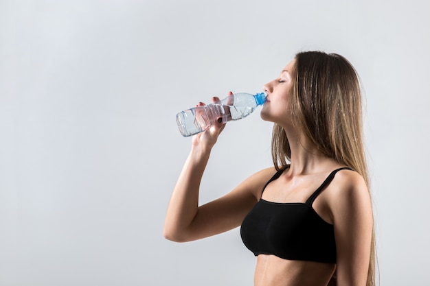 Sporty girl drinking water after sport training