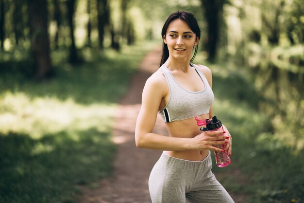 Sporty girl drinking water in park