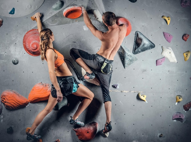 Sporty male and female climbing on a climbing  wall.