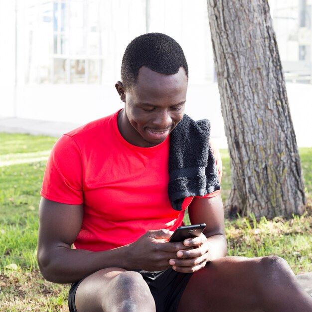 Sporty man in park looking at smartphone