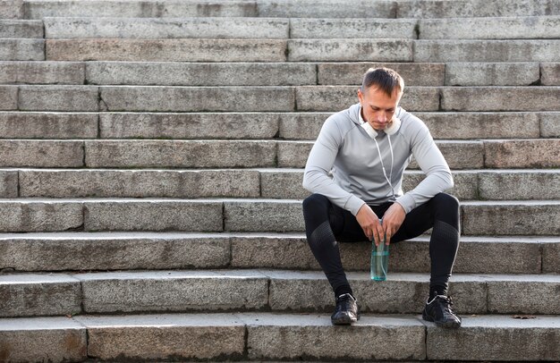 Sporty man resting on stairs